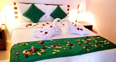two swans sitting on a bed with flowers on it at Sun Shoot Villas Seminyak in Seminyak
