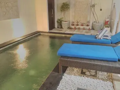 an indoor pool with green water in a room at Sun Shoot Villas Seminyak in Seminyak