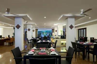 a restaurant with tables and chairs in a room at Hotel Santika Kuta in Kuta