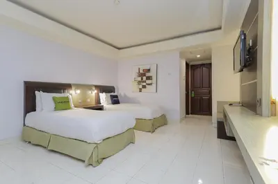 a hotel room with two beds and a television at Urbanview Hotel Taman Suci Denpasar Bali in Denpasar