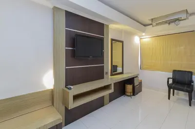 a hotel room with a flat screen tv and a chair at Urbanview Hotel Taman Suci Denpasar Bali in Denpasar