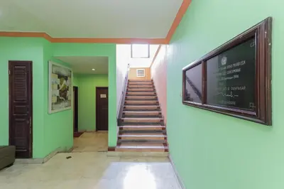 a hallway with a staircase with green walls and a sign at Urbanview Hotel Taman Suci Denpasar Bali in Denpasar