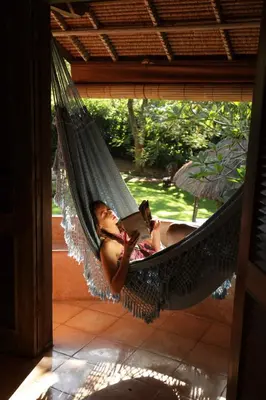 a woman laying in a hammock with a dog at Villa Bella Bali - Authentic Balinese Luxury Villa with Tropical Elegance - Nanny and Cook in Canggu