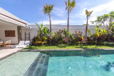 a swimming pool next to a house with palm trees at Villa Nala - Amazing 3-Bedroom in Seminyak in Seminyak