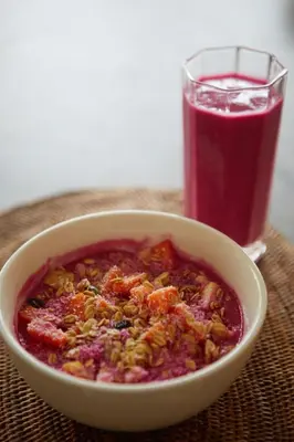 a bowl of food and a glass of red drink at Ahimsa Beach in Jimbaran