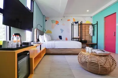 a bedroom with a bed and a tv and a table at Cara Cara Inn in Kuta