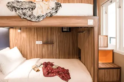 a bedroom with two bunk beds with white sheets at Cara Cara Inn in Kuta