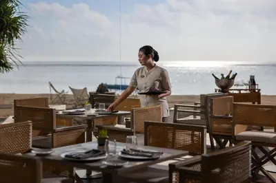 a woman standing at a table at the beach at Sadara Resort in Nusa Dua