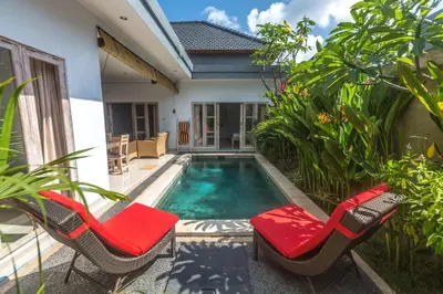 a swimming pool with two chairs and a house at Castro Villa in Seminyak