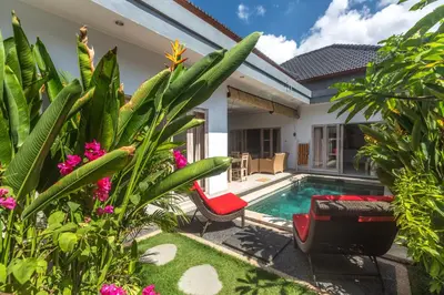 a villa with a swimming pool and a garden at Castro Villa in Seminyak