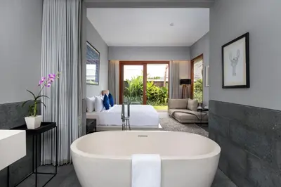 a bathroom with a bath tub and a bedroom at Amarin Seminyak in Seminyak