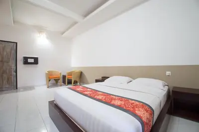 a bedroom with a large bed and chairs in it at Adikara Renon in Denpasar
