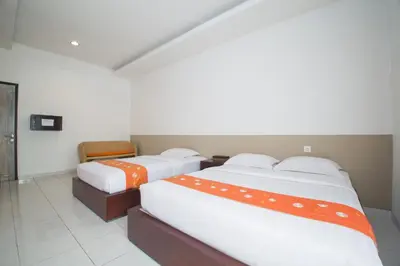 two beds with orange and white sheets in a room at Adikara Renon in Denpasar