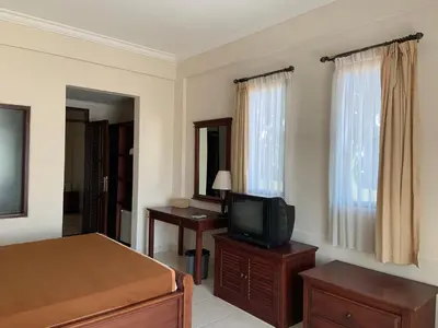 a bedroom with a bed and a tv on a dresser at Nirwana Suites in Denpasar