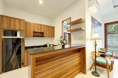 a kitchen with wooden cabinets and a counter top at Lucia Villa Seminyak Beachside By Bali Asia Villa in Seminyak