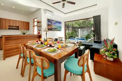 a kitchen and living room with a wooden table and chairs at Lucia Villa Seminyak Beachside By Bali Asia Villa in Seminyak