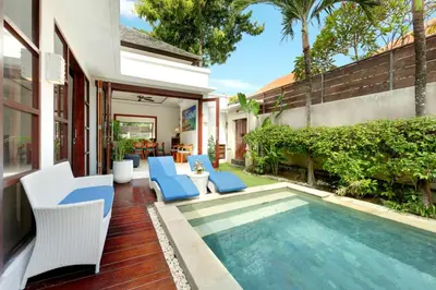 a backyard with a pool and chairs and a house at Lucia Villa Seminyak Beachside By Bali Asia Villa in Seminyak