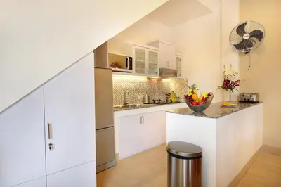 a kitchen with white cabinets and a counter top at De Liza Villa Seminyak Beachside By Bali Asia Villa in Seminyak