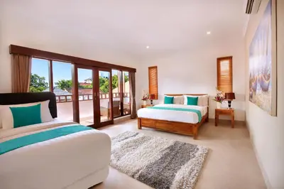 a bedroom with two beds and a balcony at De Liza Villa Seminyak Beachside By Bali Asia Villa in Seminyak