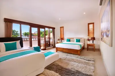 a bedroom with two beds and a balcony at De Liza Villa Seminyak Beachside By Bali Asia Villa in Seminyak