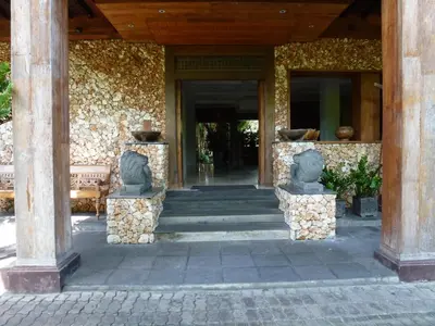 an entrance to a building with statues on pillars at Hotel Puri Bambu in Jimbaran
