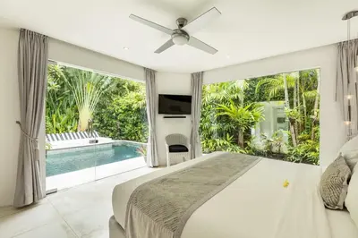 a bedroom with a large bed and a pool at Esha Villa Drupadi Seminyak in Seminyak