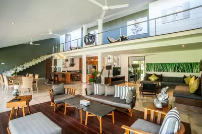 a living room with couches and chairs and a staircase at Kamehameha Luxury Villa in Seminyak