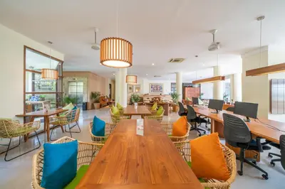 a restaurant with wooden tables and chairs in a room at Sara Residence by Nakula in Legian