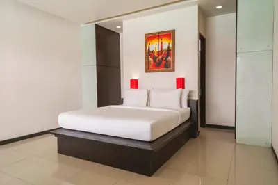 a bedroom with a white bed with a painting on the wall at Swiss-Belcourt Sunset in Seminyak