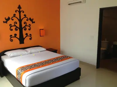a bedroom with a white bed with an orange wall at Dewi Sri Hotel in Legian