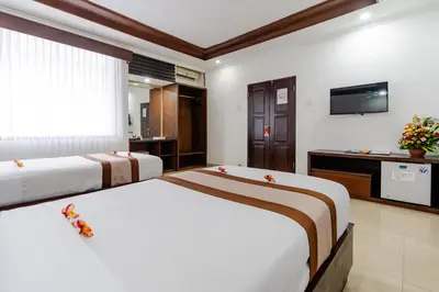 a hotel room with two beds and a television at Dewi Sri Hotel in Legian
