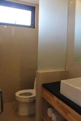 a bathroom with a toilet and a sink and a window at Hotel Karthi Kuta in Kuta