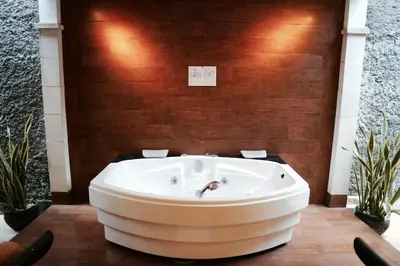a bath tub in a room with a wooden wall at The Lagoon Bali Pool Hotel and Suites in Legian