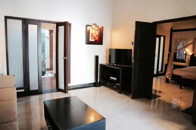 a living room with a tv and a black coffee table at The Lagoon Bali Pool Hotel and Suites in Legian