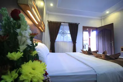 a bedroom with a large bed with white sheets and flowers at Bakung Sari Resort in Kuta