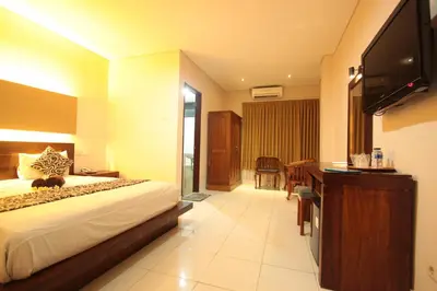 a hotel room with a bed and a flat screen tv at Bakung Sari Resort in Kuta