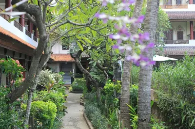 a walkway through a garden with trees and flowers at Bakung Sari Resort in Kuta