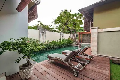 a pair of chairs sitting on a deck next to a pool at Pradha Villas Seminyak in Seminyak