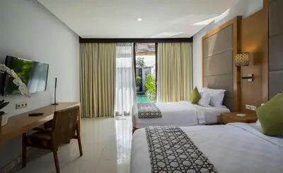 a hotel room with two beds and a desk and a television at Pradha Villas Seminyak in Seminyak