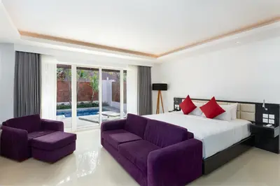 a bedroom with a large bed and two purple chairs at Downtown Villas in Seminyak