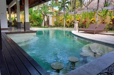 a swimming pool with two chairs in a house at The Maya Seminyak Villas in Seminyak