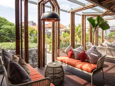 a porch with a couch and chairs and a table at Baleka Resort & Spa in Legian