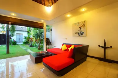 a living room with a red couch and a table at Villa Calypso by Optimum Bali Villas in Seminyak