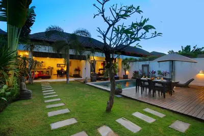 a backyard with a table and chairs and a house at Villa Calypso by Optimum Bali Villas in Seminyak