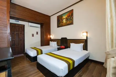 a hotel room with two beds and a tv at The Flora Kuta Bali in Kuta