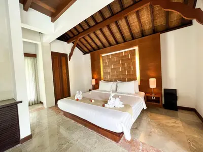 a bedroom with a large bed with white sheets at The Wangsa Benoa in Nusa Dua