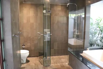 a bathroom with a glass shower with a toilet at Nunia Boutique Villa in Seminyak