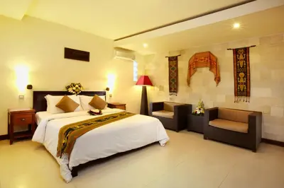 a bedroom with a large white bed and a chair at Putu Bali Villa & Spa in Seminyak