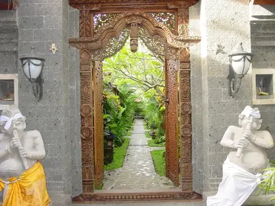 an ornate doorway to a garden with two statues at Putu Bali Villa & Spa in Seminyak