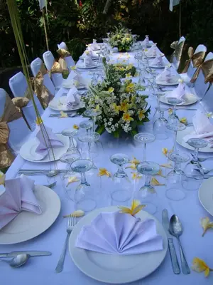 a long table with white plates and flowers on it at Villa Coco Bali in Seminyak